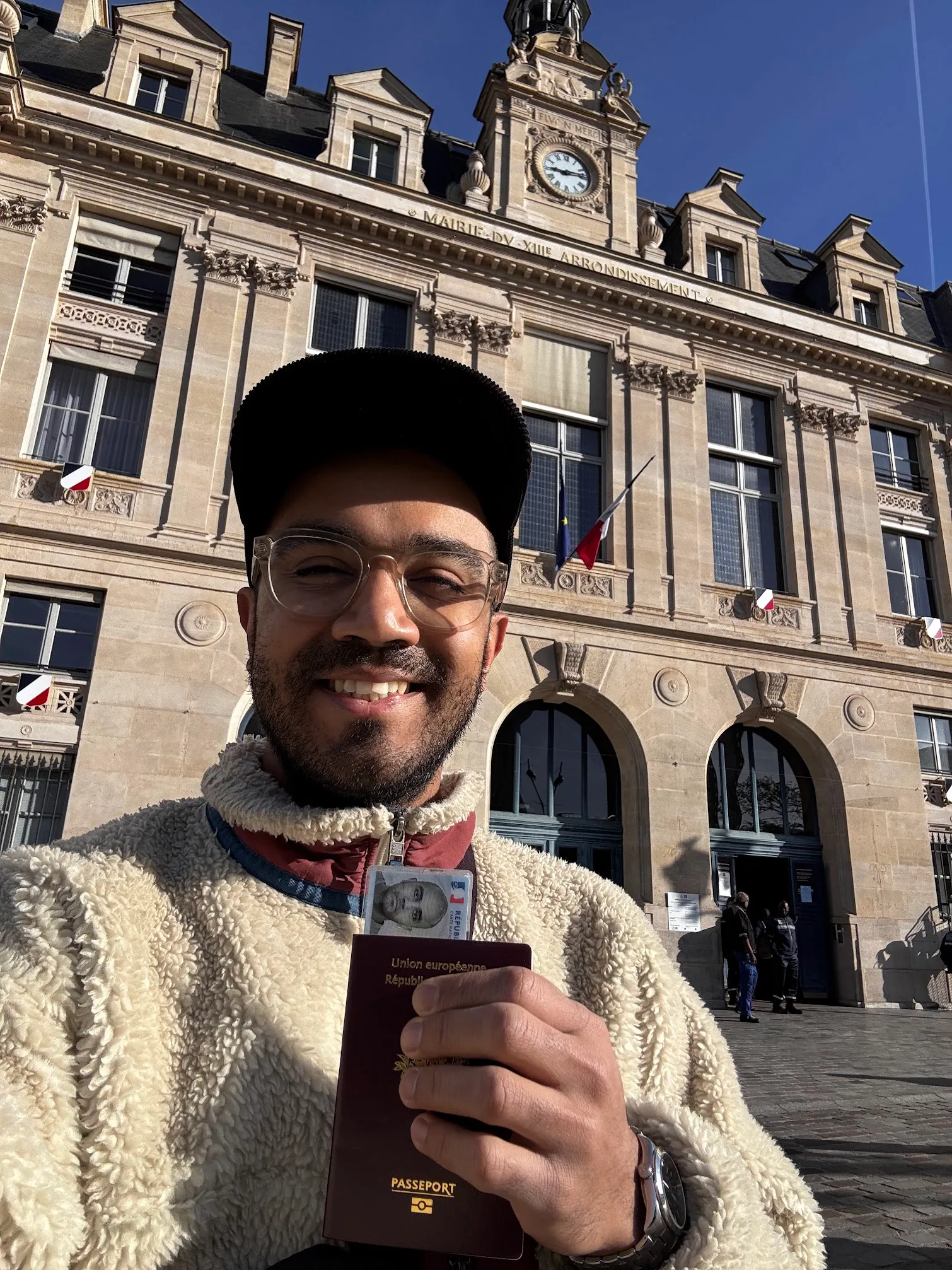 Mayank holding his new French passport and ID card in front of the Mairie du XVIIIe arrondissement in Paris